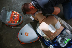 Group of medical students and a doctor in scrubs discussing notes and collaborating around a table in a classroom or hospital setting.