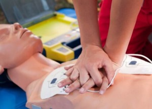 Person assisting an unconscious man lying on the floor, demonstrating the recovery position for first aid.