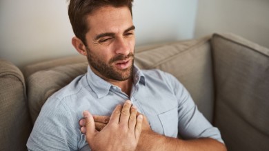 Person assisting an unconscious man lying on the floor, demonstrating the recovery position for first aid.