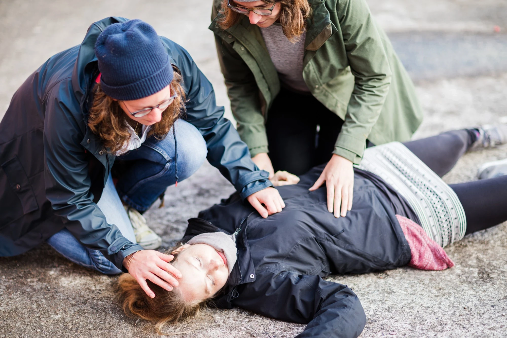 2 persons checking an unconscious woman
