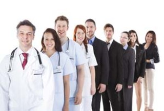 A group of professionals standing in a line, including doctors in lab coats and business people in formal attire, against a white background.