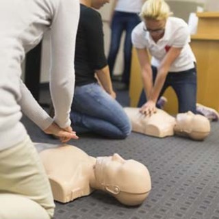 People practicing CPR on training mannequins during a first aid class.