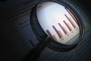 Magnifying glass focusing on a bar graph with vertical bars of varying heights on a printed document.