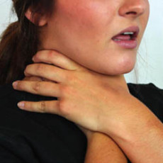 Woman holding her throat with both hands, appearing to experience difficulty breathing or choking.