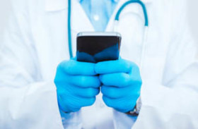 Doctor wearing blue gloves and a white coat uses a smartphone, with a stethoscope visible around their neck.