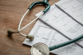 A stethoscope resting on top of medical test result papers on a wooden surface.