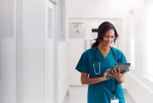 healthcare-professional-along-hospital-hallway-using-a-laptop-while-checking-on-patients-records.