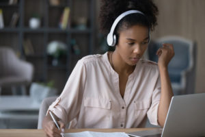 woman-wearing-headset-infront-of-laptop-holding-a-pen