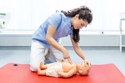 a female doing compressions on an infant mannequin