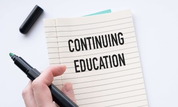 a hand holds a black marker and the other a spiral-bound paper with the words Continuing Education in bold, black, all caps font
