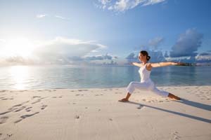woman doing warrior yoga pose on beach