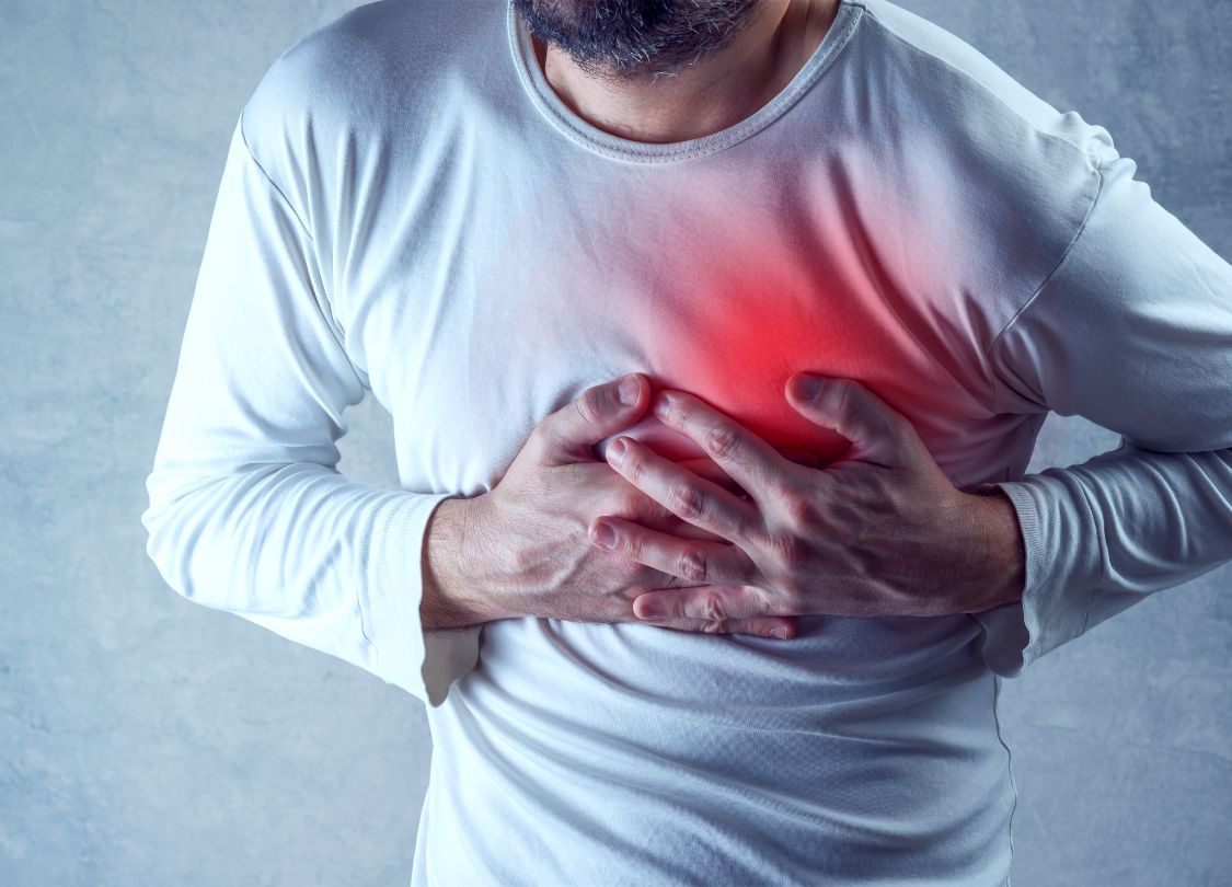 Man clutching chest in pain, illustrating symptoms of acute coronary syndrome managed by ACLS Algorithms.