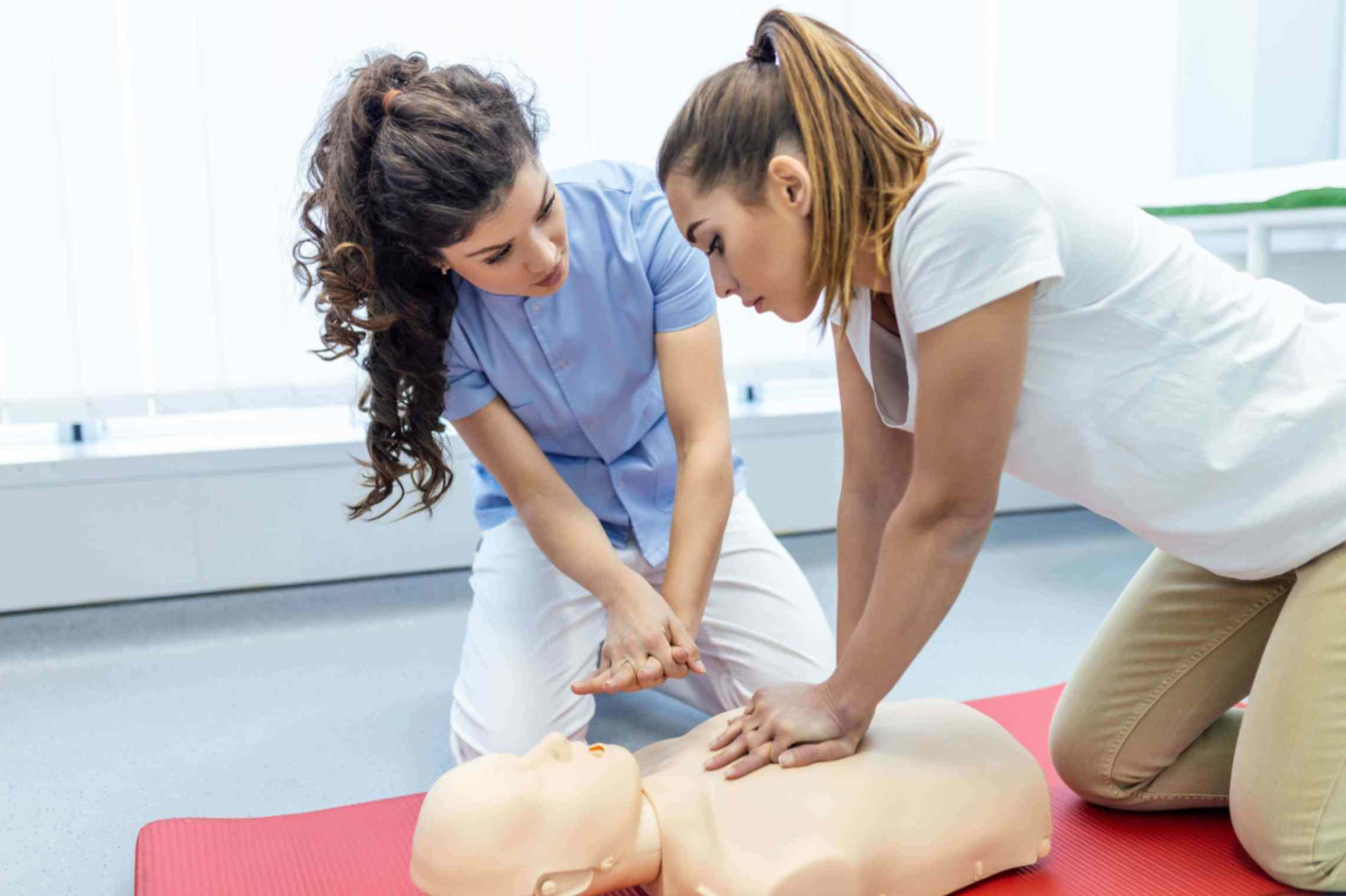 Two women performing CPR on a mannequin