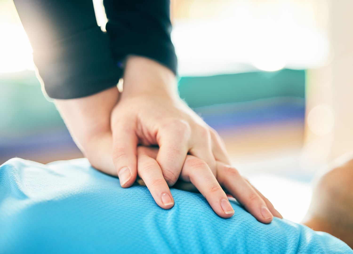 CPR being performed with hands placed on the chest of a patient wearing a blue shirt during an emergency situation.