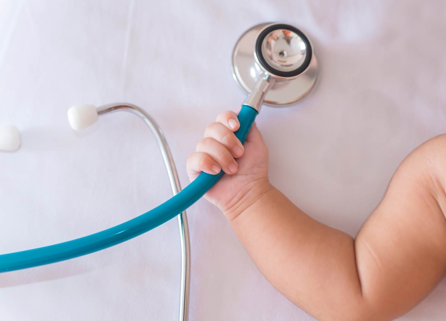 Close-up of a baby's hand holding a stethoscope.