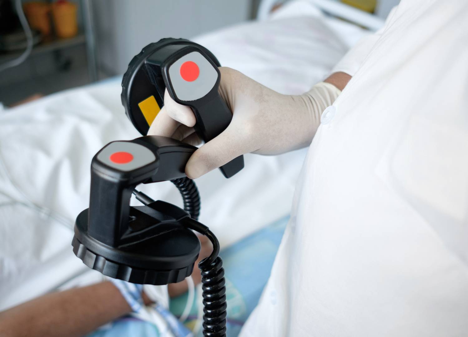 Healthcare professional holding defibrillator paddles, preparing for synchronized cardioversion to treat abnormal heart rhythms.