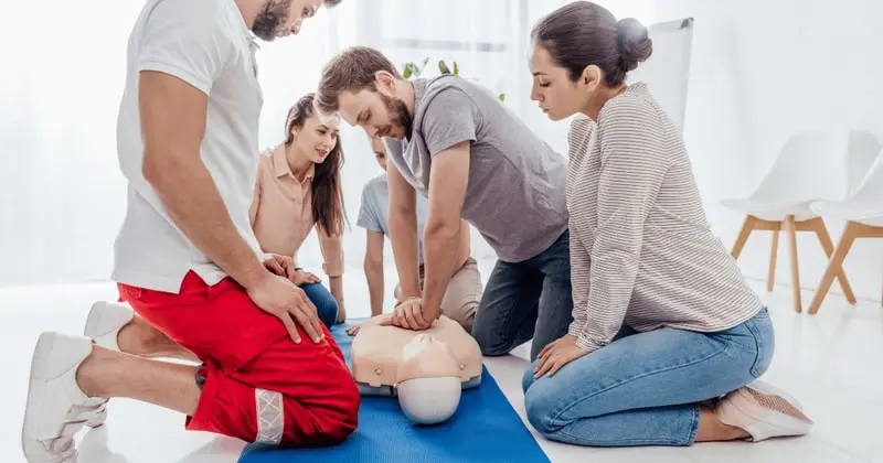Group of men and women practicing cpr compressions using a mannequin
