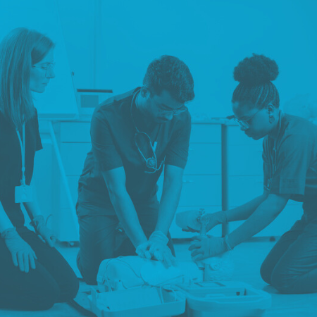 Three medical personnel practice ACLS on a medical mannequin for medical course training
